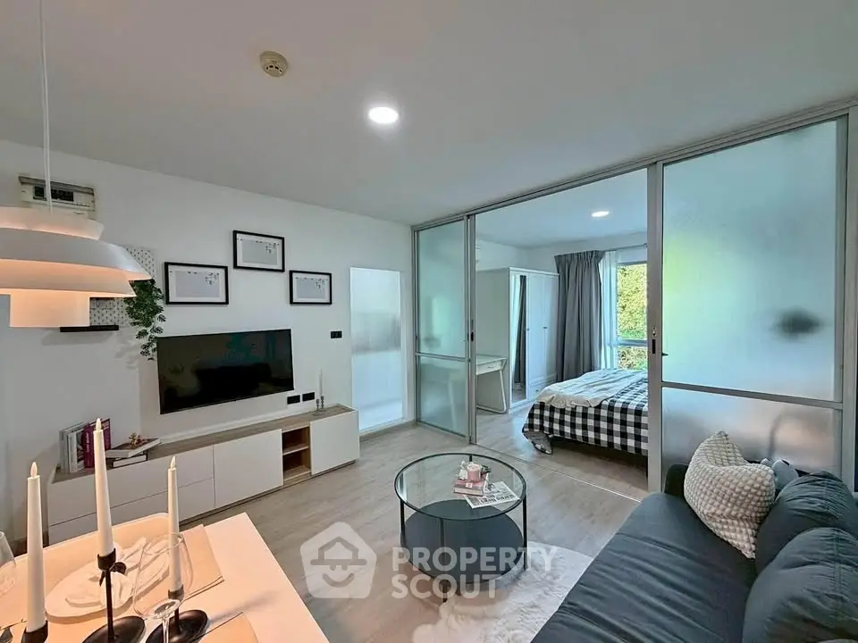 Modern open-plan living room with stylish decor and sliding glass doors to bedroom.