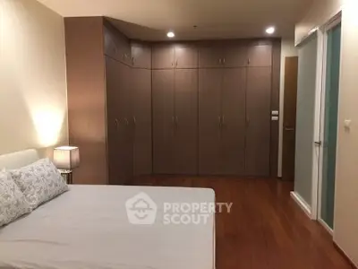 Spacious bedroom with elegant wooden flooring and ample closet space.