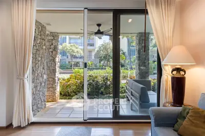 Luxurious living room with sliding glass doors opening to a serene garden view, perfect for relaxation.