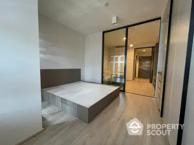 Spacious bedroom with modern design, featuring a large bed, wooden flooring, and glass partition leading to a well-lit corridor.