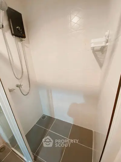 Modern shower area with sleek tiles and showerhead in a minimalist bathroom design.