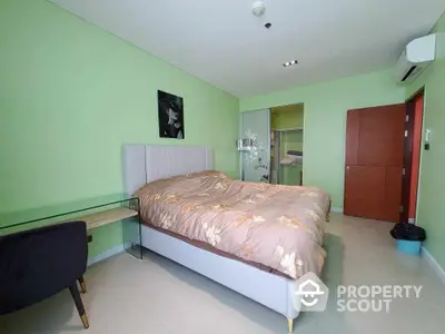 Spacious bedroom with modern decor and green walls, featuring a comfortable bed and sleek furniture.