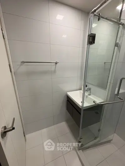 Modern bathroom with glass shower and sleek vanity in contemporary apartment.
