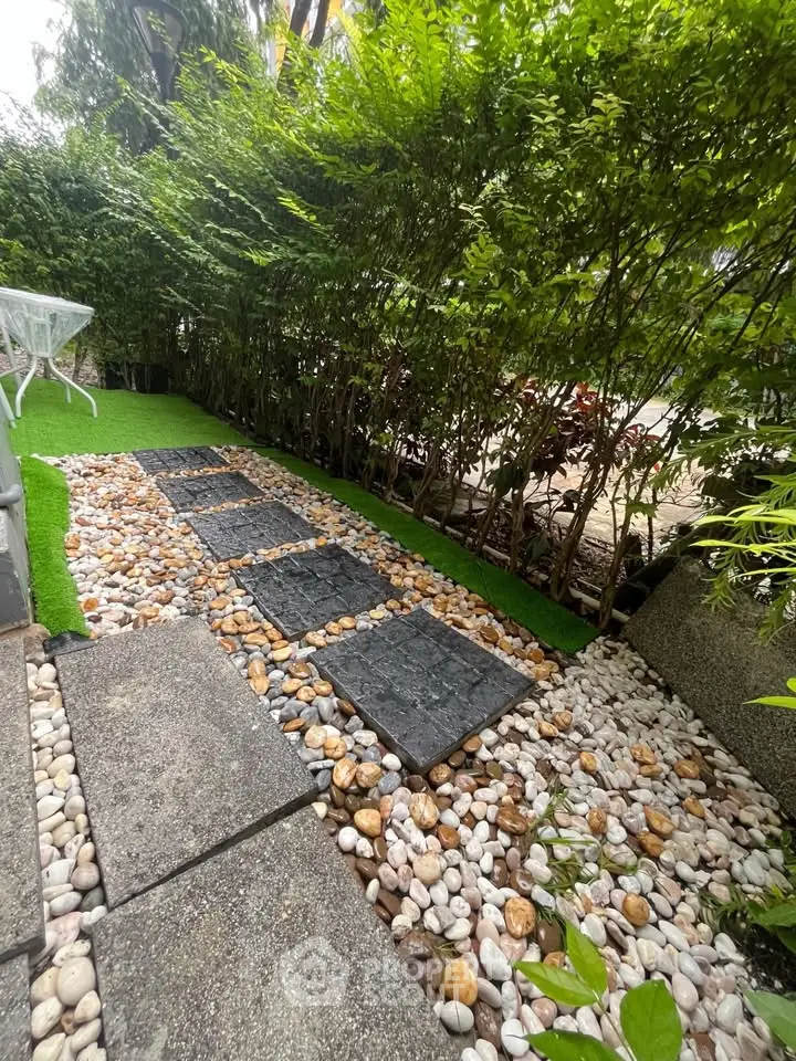 Charming garden pathway with stone and pebble design, surrounded by lush greenery, perfect for tranquil outdoor living.