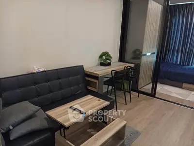 Modern living room with stylish furniture and sliding glass doors leading to a cozy bedroom.