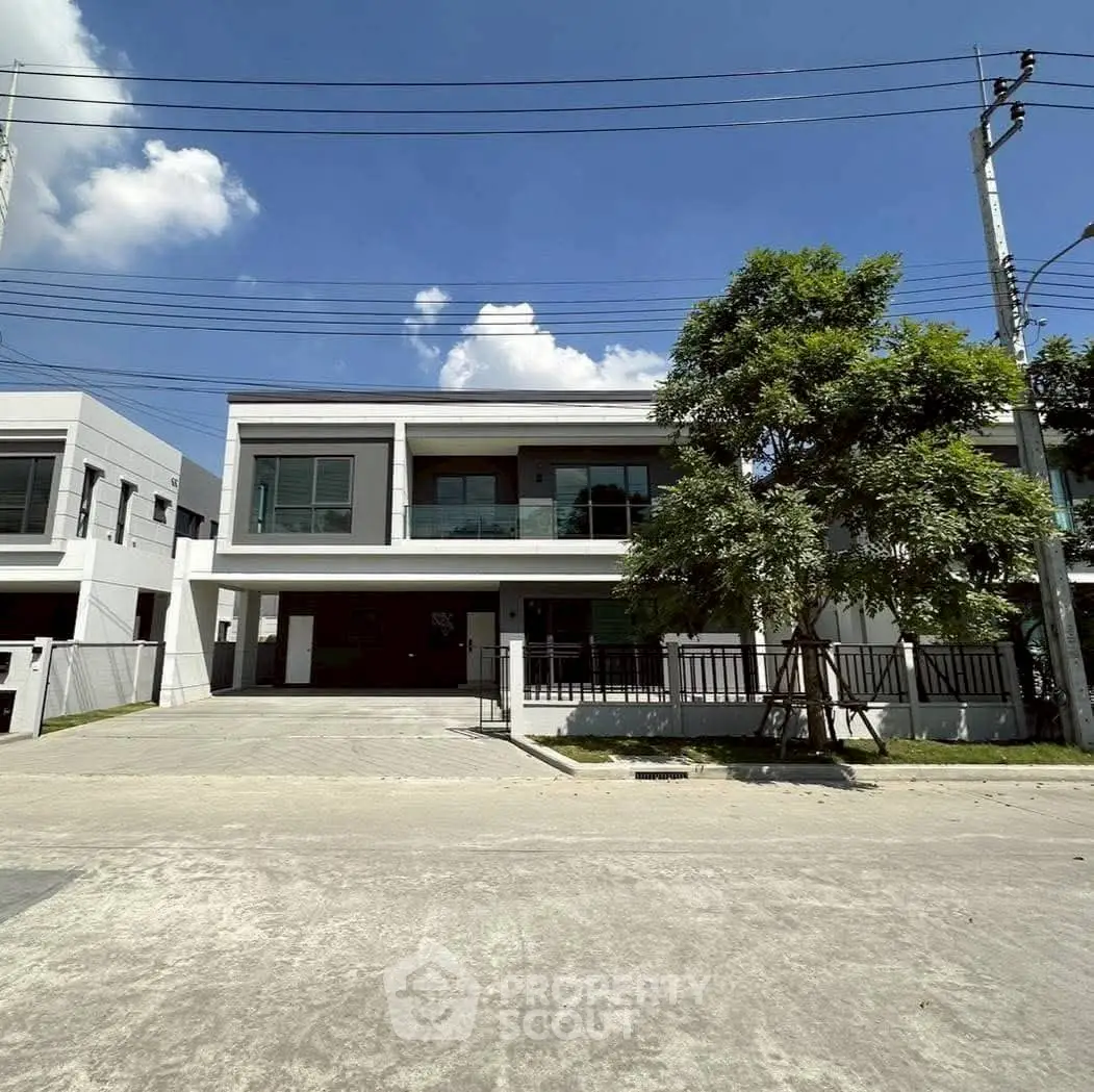 Modern two-story house with large windows and driveway under a clear blue sky.