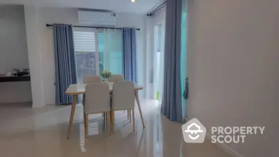 Modern dining area with elegant table and chairs, featuring large windows and blue curtains for natural light.