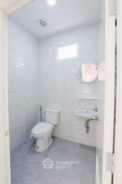 Modern minimalist bathroom with white tiles and round mirror