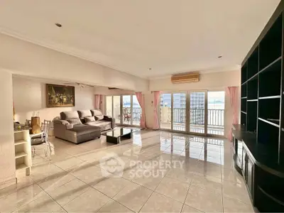 Spacious living room with large windows and balcony offering stunning city views.