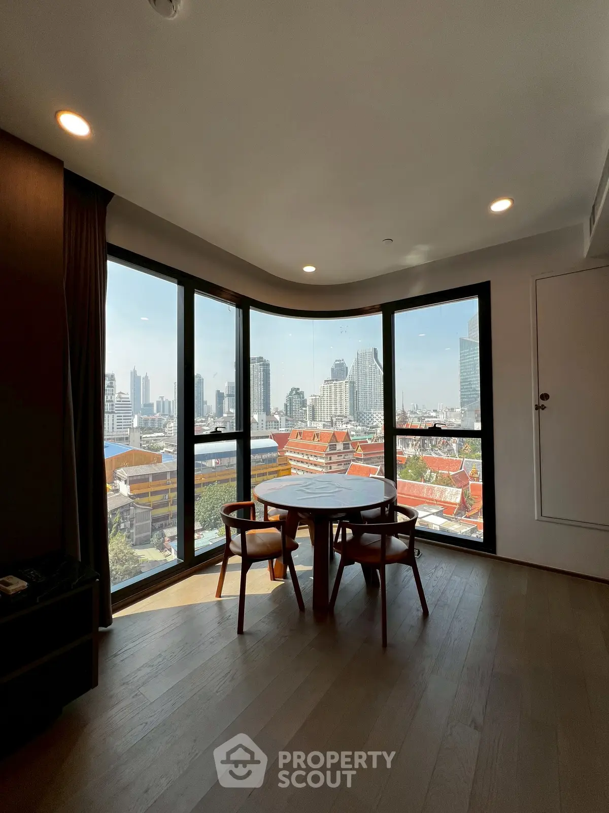 Stunning city view from modern apartment with floor-to-ceiling windows and elegant dining area.