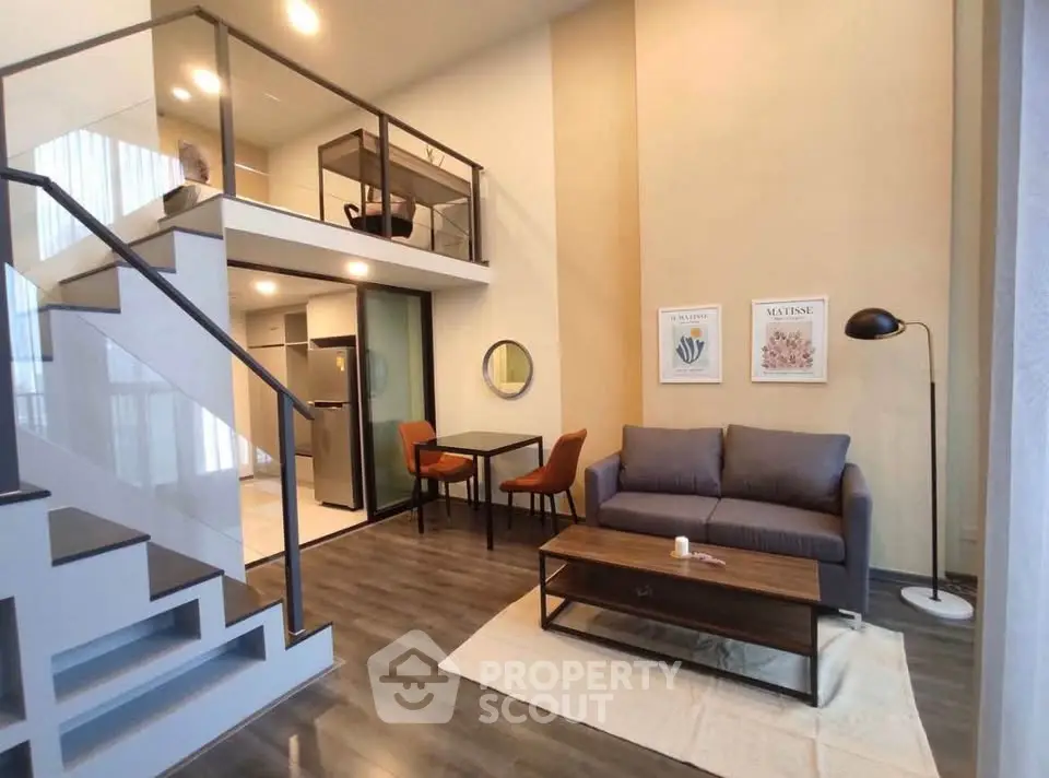 Modern loft-style living room with mezzanine, sleek furniture, and open kitchen layout.