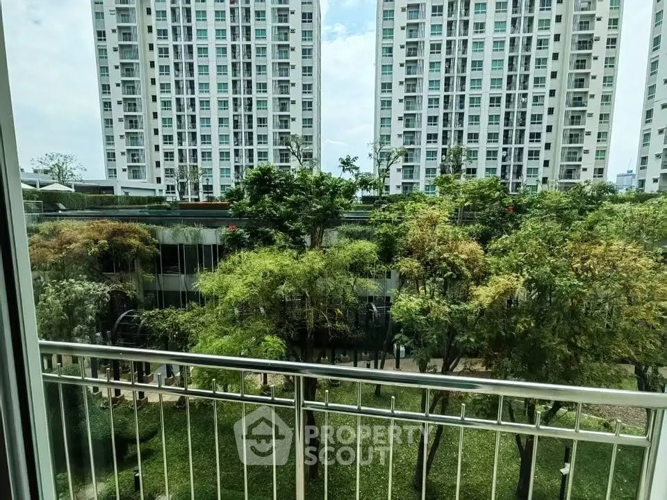 Stunning view from balcony overlooking lush garden and modern high-rise buildings.