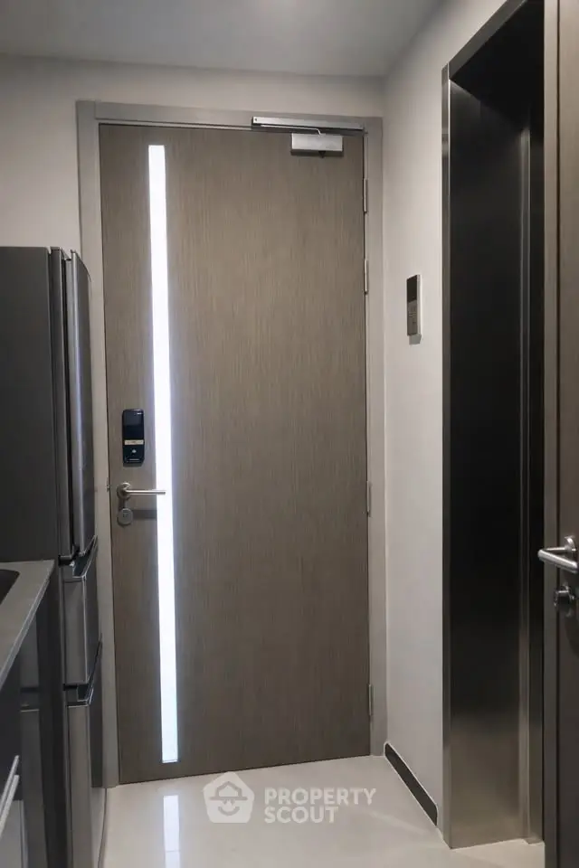 Modern apartment entrance with sleek door and stainless steel appliances.