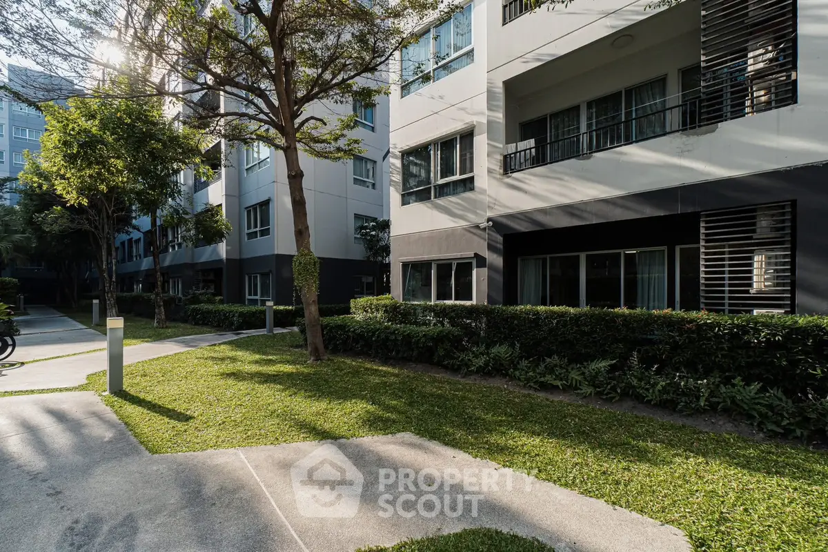 Modern apartment building exterior with lush greenery and sunlight