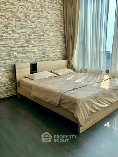 Modern bedroom with large windows and stylish stone accent wall in high-rise apartment.