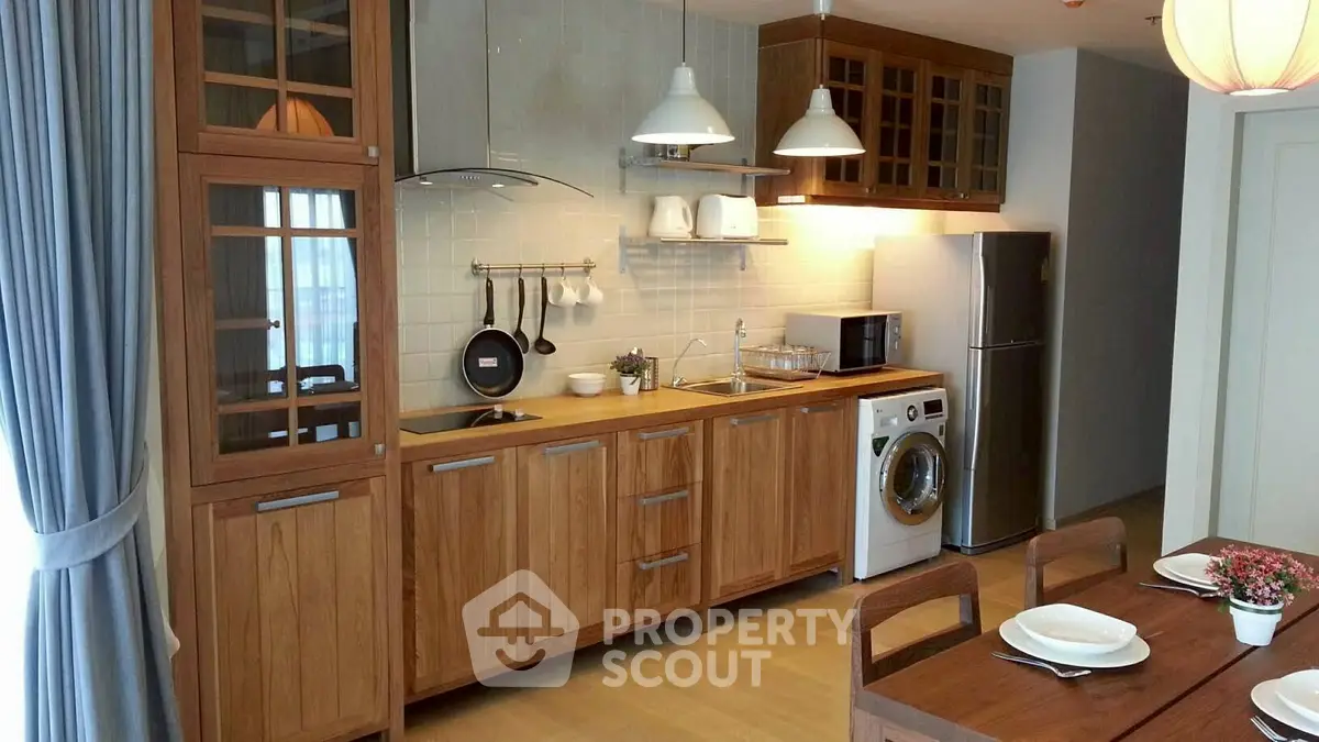 Modern kitchen with wooden cabinets, washing machine, and dining area