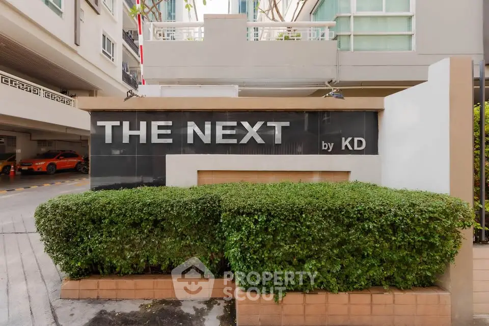 Modern condominium entrance with lush greenery and sleek signage