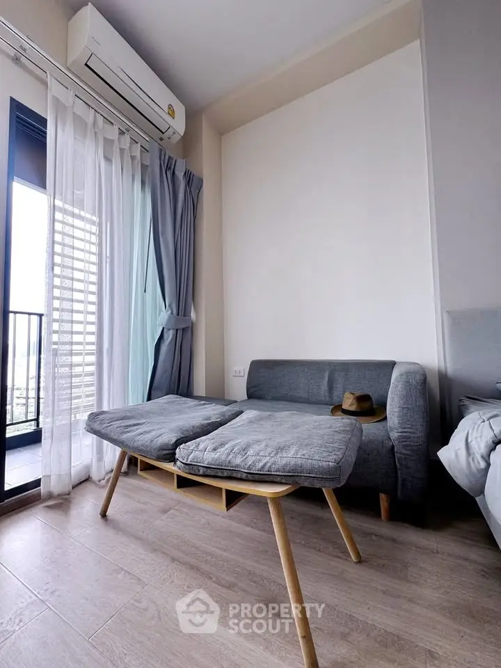 Modern living room with stylish sofa and balcony view, featuring sleek air conditioning unit and elegant curtains.