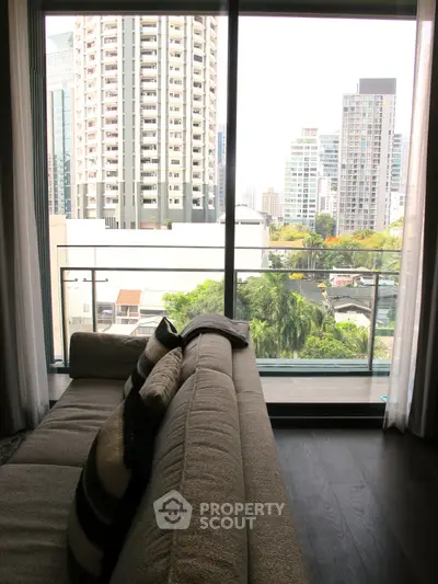 Modern living room with large windows offering stunning city views and cozy seating area.