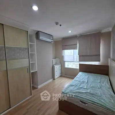 Cozy bedroom with wooden flooring, built-in wardrobe, and large window for natural light.