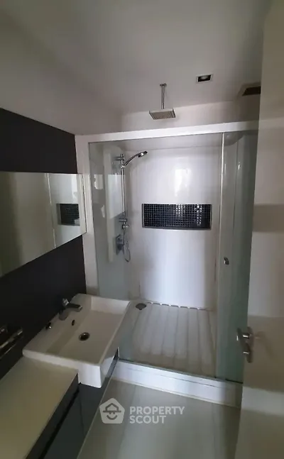 Modern bathroom with sleek shower and stylish sink in contemporary apartment.