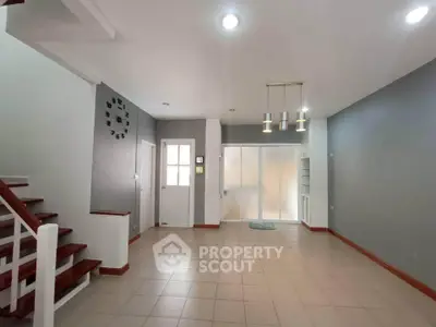 Spacious modern living room with stylish lighting and staircase, perfect for family gatherings.