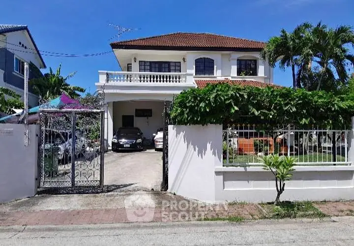 Charming two-story house with a spacious driveway and lush greenery, perfect for family living.