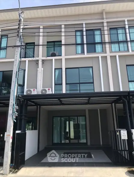 Modern townhouse exterior with large windows and covered parking area.