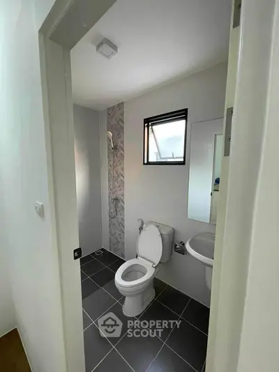 Modern bathroom with sleek design and natural light, featuring a shower and toilet.