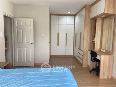 Spacious bedroom with modern built-in wardrobe and study area, featuring elegant wood finishes and a cozy atmosphere.