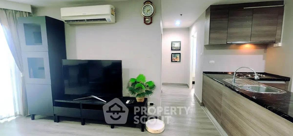 Modern living room with sleek kitchen, large TV, and stylish decor in a contemporary apartment.