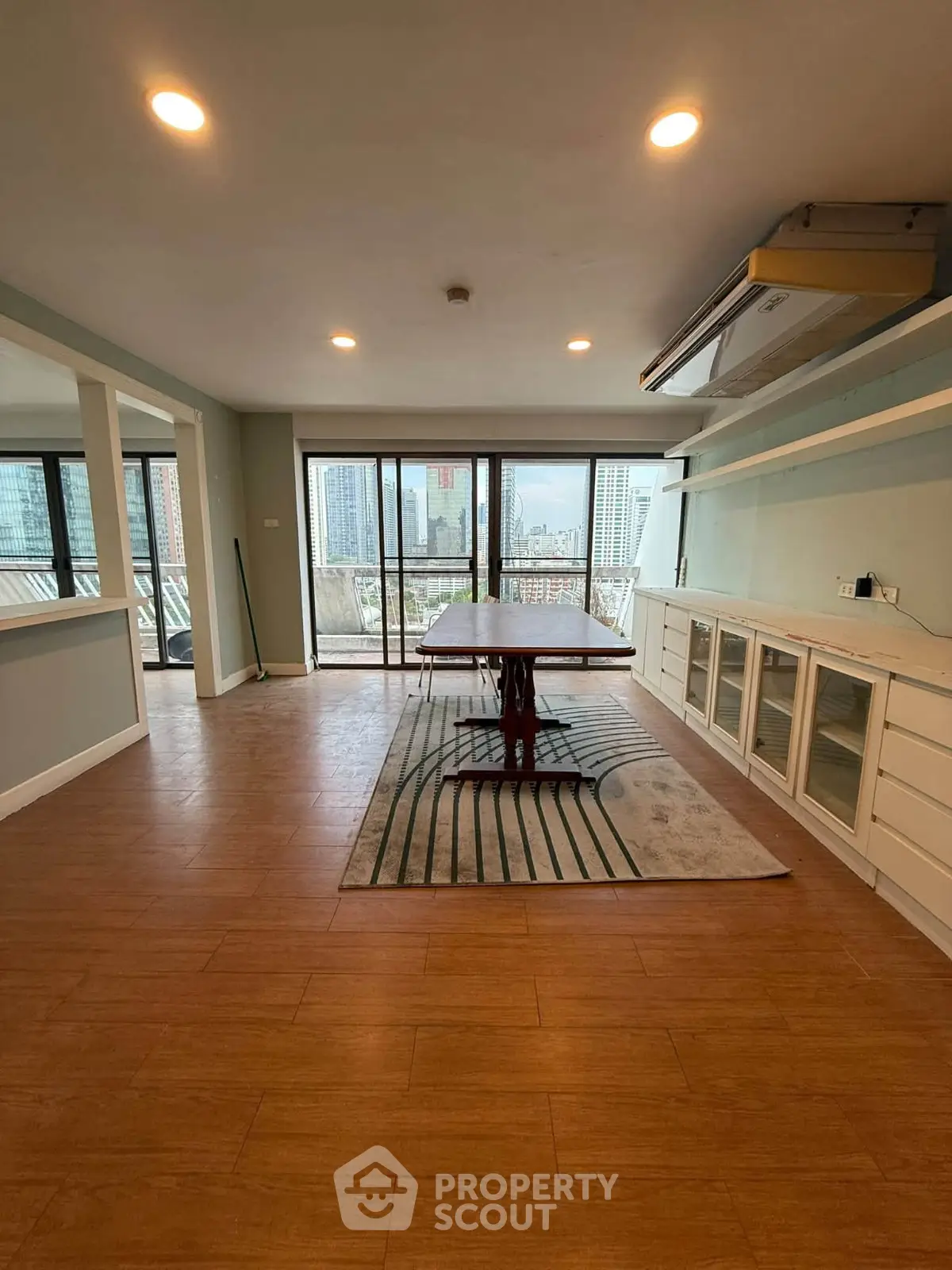 Spacious living room with city view and large windows in modern apartment.