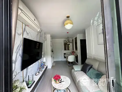 Modern living room with stylish decor and marble accents, featuring a cozy sofa and wall-mounted TV.