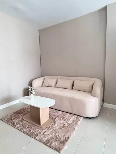 Modern minimalist living room with stylish beige sofa and sleek coffee table on plush rug.