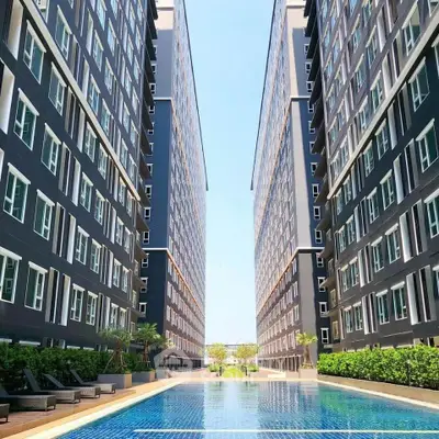 Luxurious modern apartment complex with stunning pool and lush greenery.