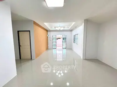 Spacious modern living room with glossy tiled floors and elegant lighting.