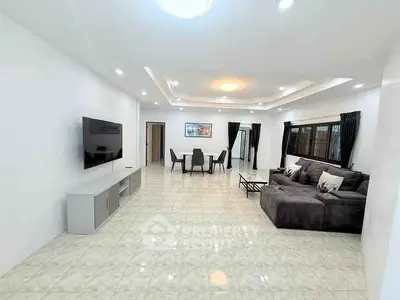 Spacious modern living room with sleek furniture and large TV, perfect for family gatherings.