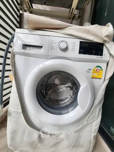 Modern washing machine on a balcony with sleek design and energy efficiency label.