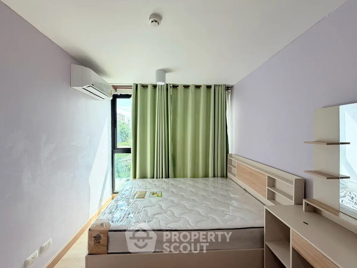 Spacious bedroom with large window and modern furnishings, perfect for comfortable living.