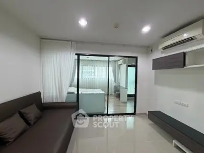 Modern living room with sleek design and glass partition leading to bedroom