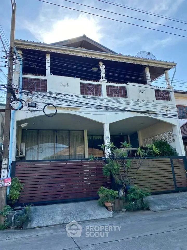 Charming two-story house with balcony and gated entrance in a suburban neighborhood.