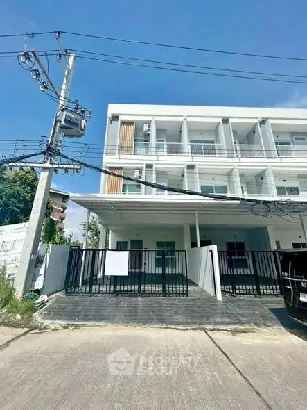 Modern three-story building with gated entrance and balconies, ideal for residential or commercial use.