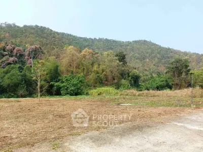 Scenic land plot with lush greenery and mountain backdrop, ideal for development or investment.