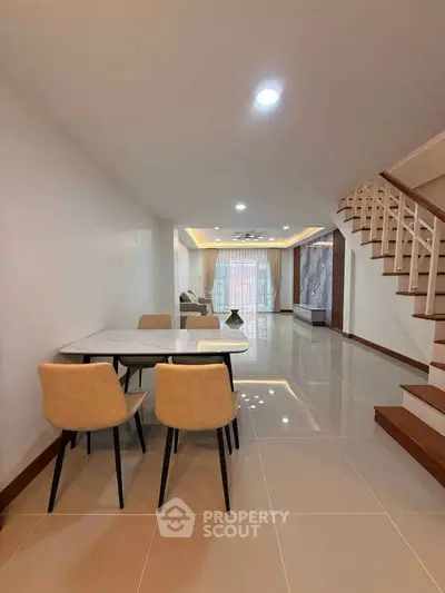 Spacious modern living room with elegant dining area and staircase, perfect for family gatherings.