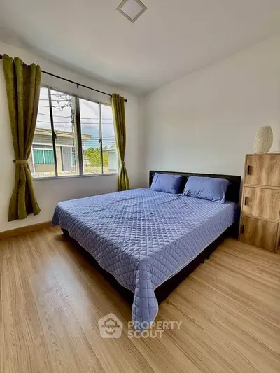 Cozy bedroom with wooden flooring and large window, featuring a comfortable bed and stylish decor.