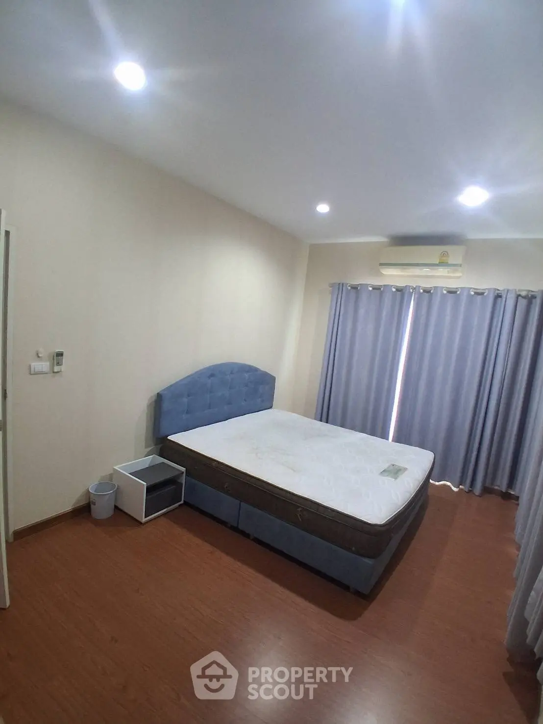 Spacious bedroom with modern design and ample natural light, featuring a comfortable bed and stylish curtains.