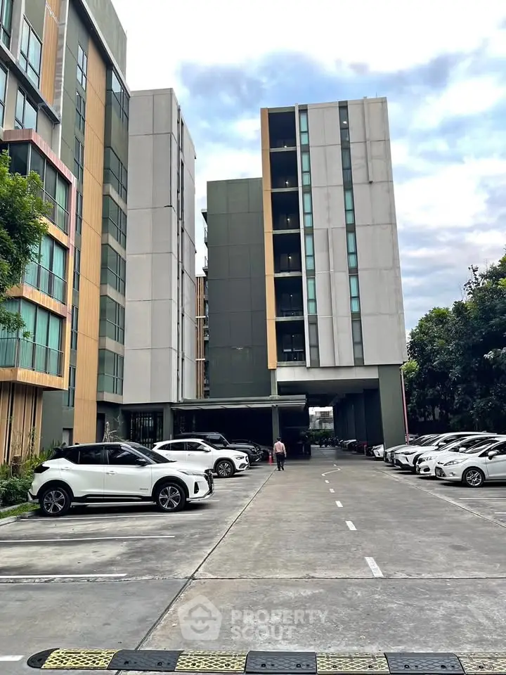 Modern apartment building with ample parking and sleek design in urban setting.