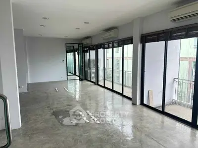 Spacious modern living room with large windows and balcony access, perfect for natural light and open views.