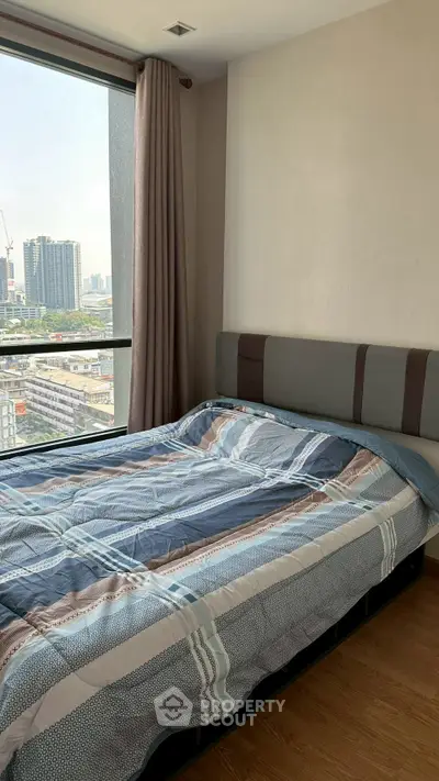 Cozy bedroom with city view and stylish bedding in modern apartment.