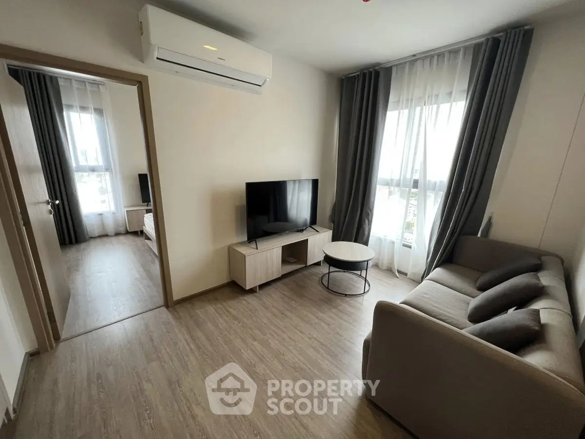 Modern living room with sleek furniture and natural light, featuring a cozy sofa and flat-screen TV.